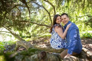 Couple posing romantically under a tree in a lush green park setting.