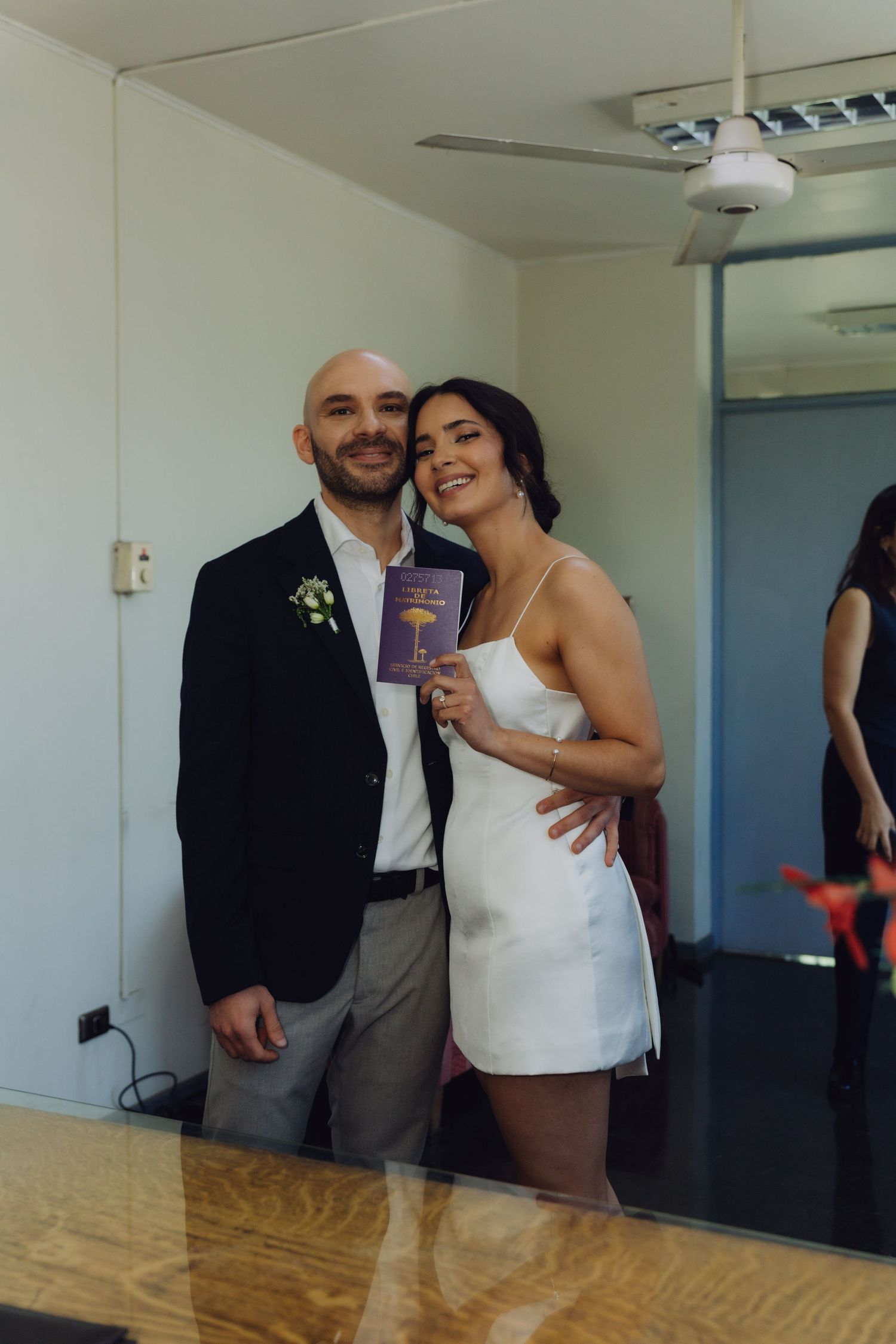 Newlywed couple poses smiling while bride holds purple marriage certificate after civil ceremony.