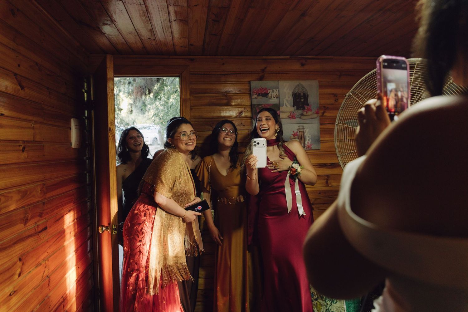 Group of elegantly dressed women posing for a photo inside a warmly lit wooden cabin.