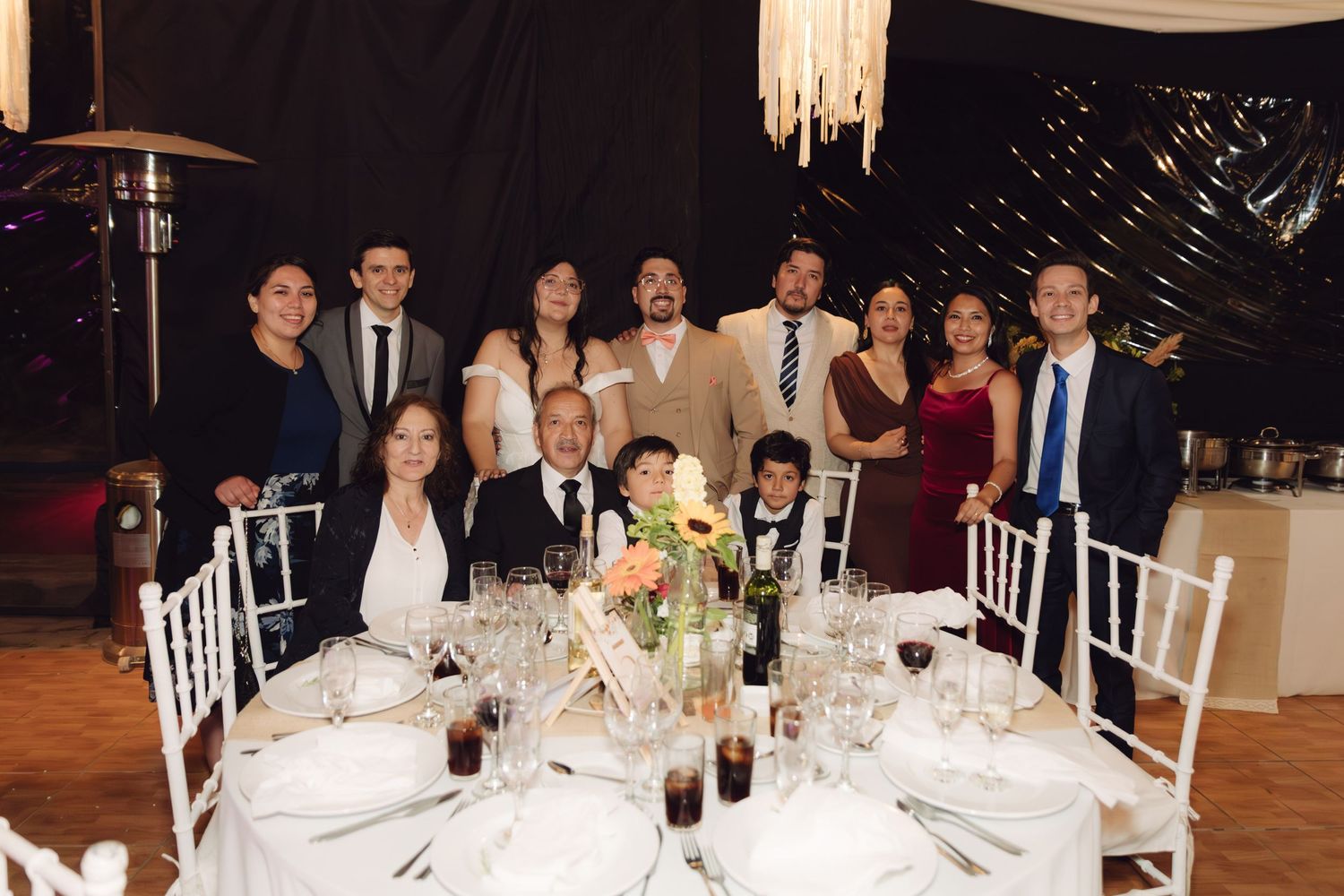 Large family group portrait at an elegant wedding reception table with floral arrangements.