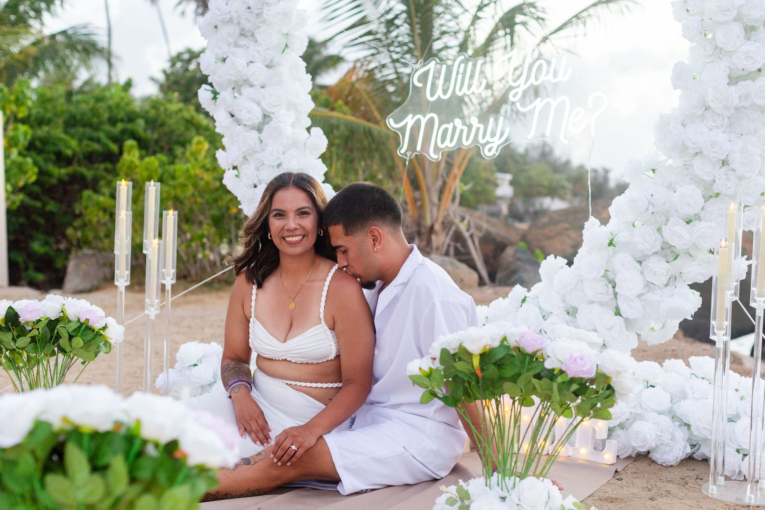 Marriage proposal. Man, woman, and decorative setup with white flower heart overlooking the ocean in Río Grande, Puerto Rico.