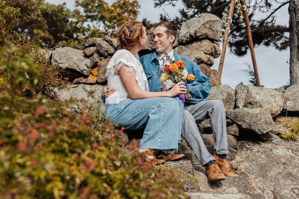 Couple sitting on stone steps sharing a romantic moment with colorful bouquet outdoors.