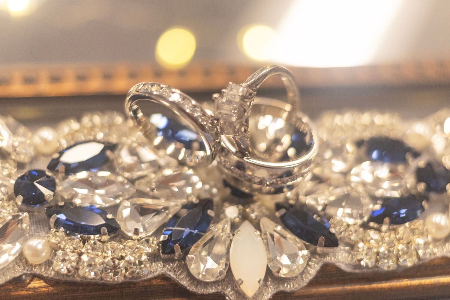Elegant diamond and sapphire jewelry set with rings and brooch displayed on a sparkling silver tray.
