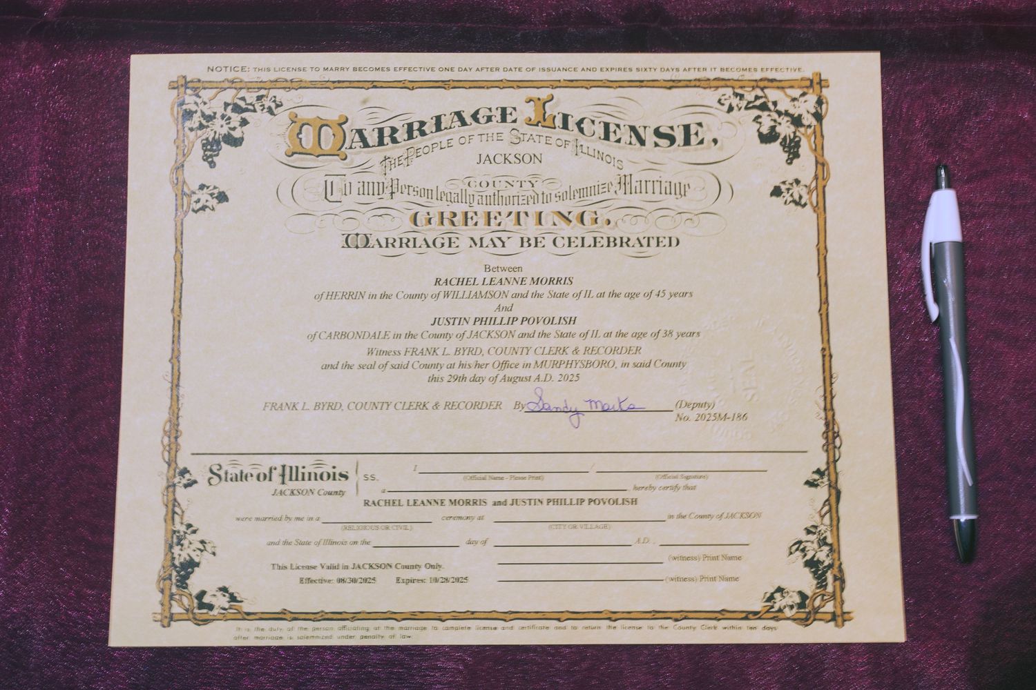 A decorative marriage license from Illinois displayed on a purple surface beside a white pen.