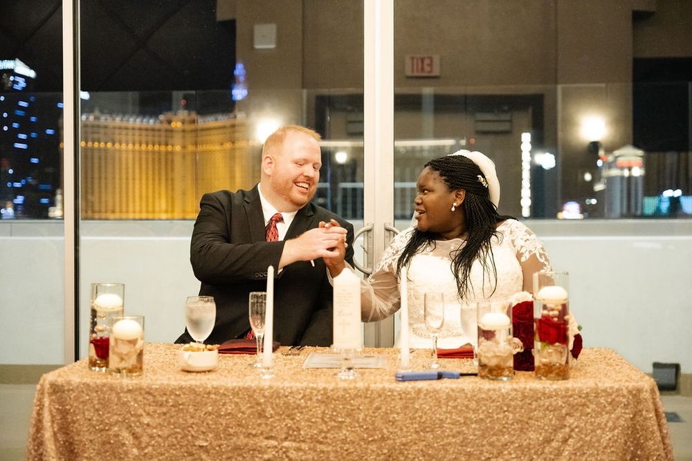 Bride and groom laughing together at sweetheart table with candles at elegant Las Vegas wedding reception.