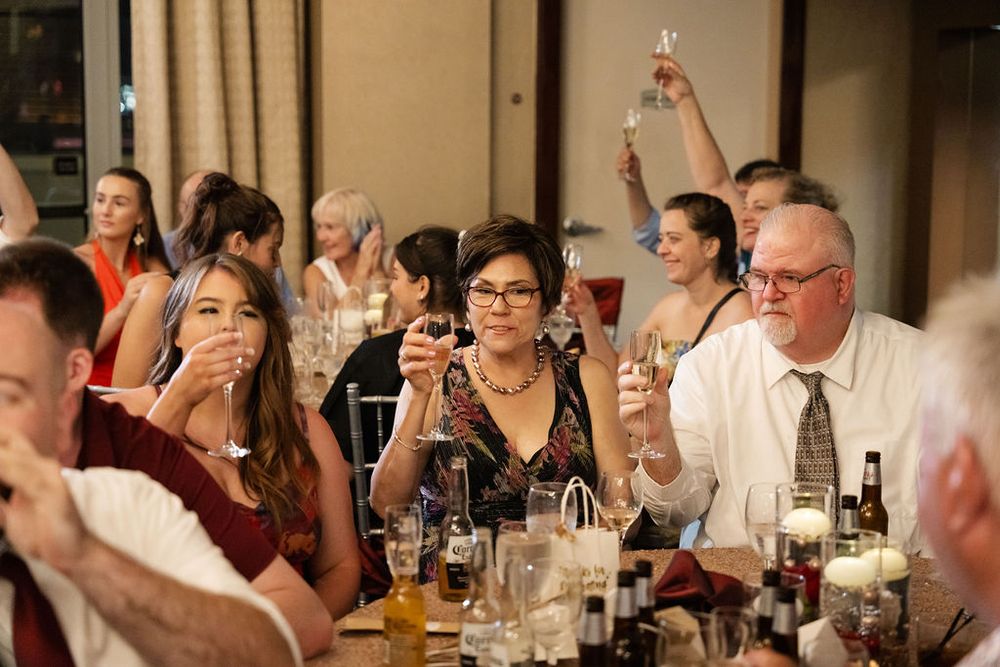 Wedding guests raise champagne glasses in a toast during a reception dinner celebration.