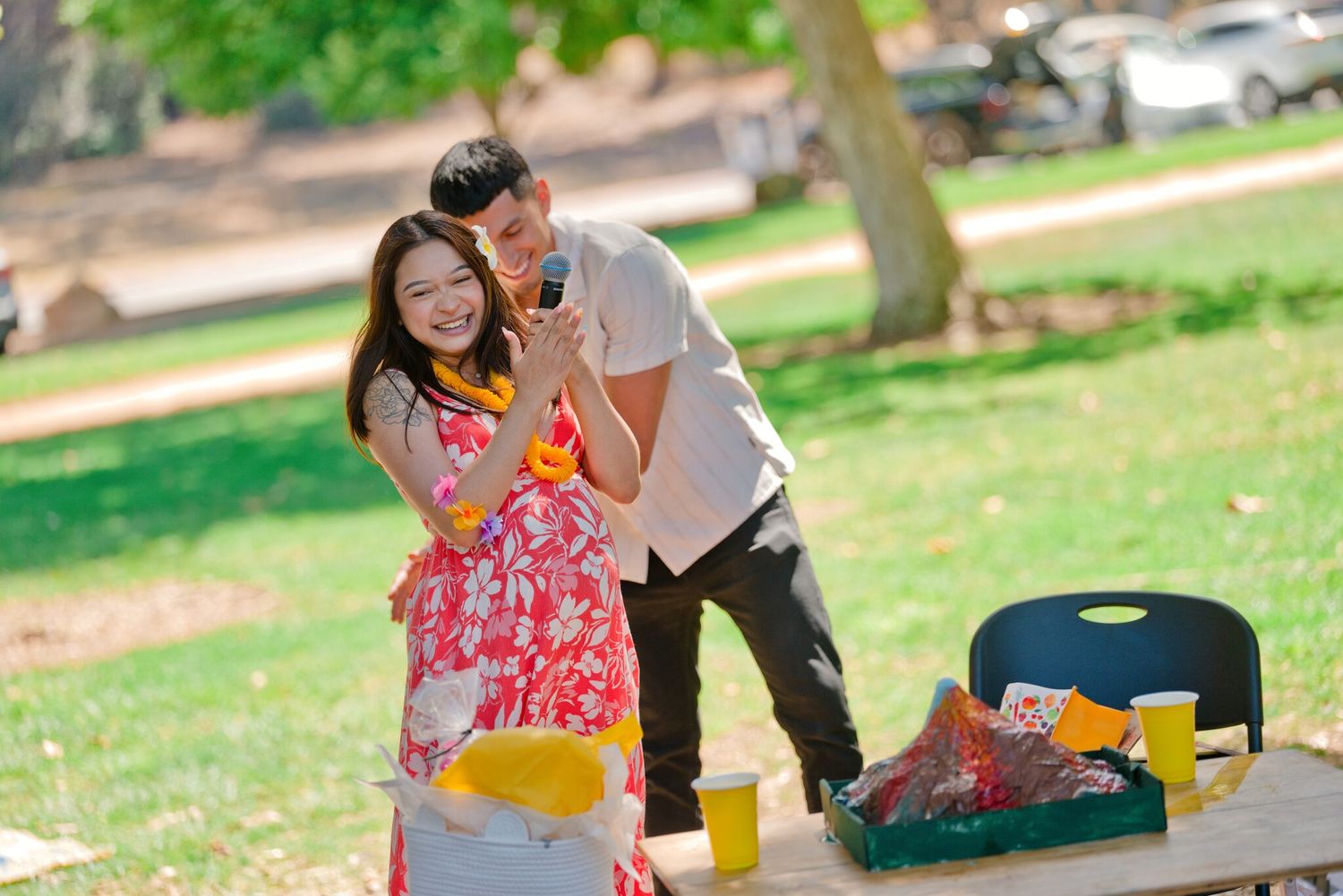 Smiling couple posing together at an outdoor park table during a festive event.
