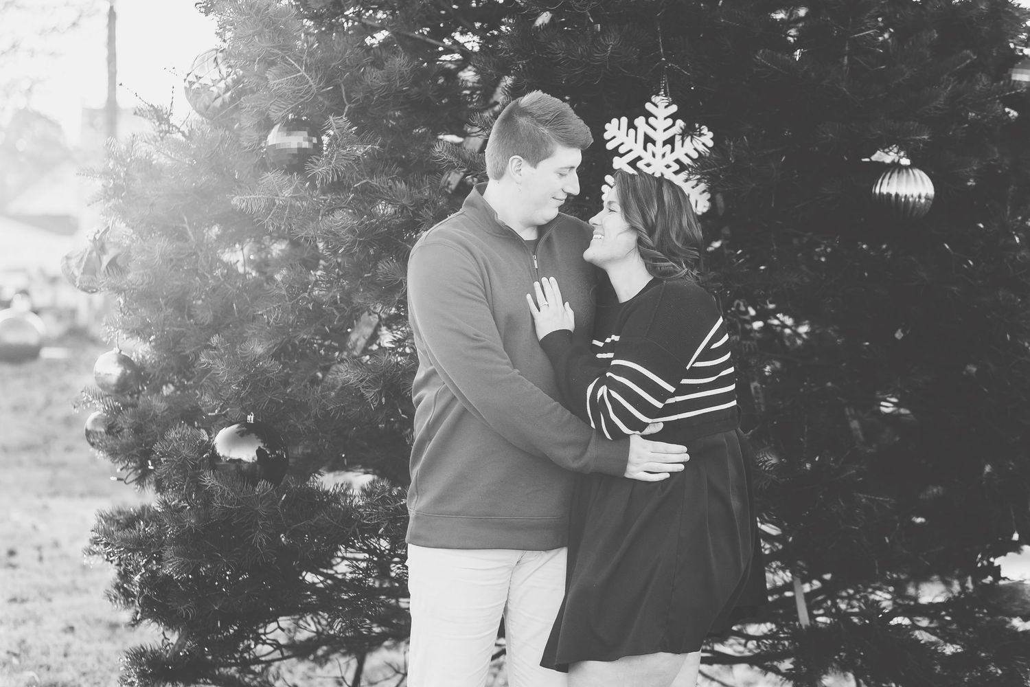 Romantic couple sharing a tender moment outdoors in warm golden light, woman in white sweater kissing man's head.