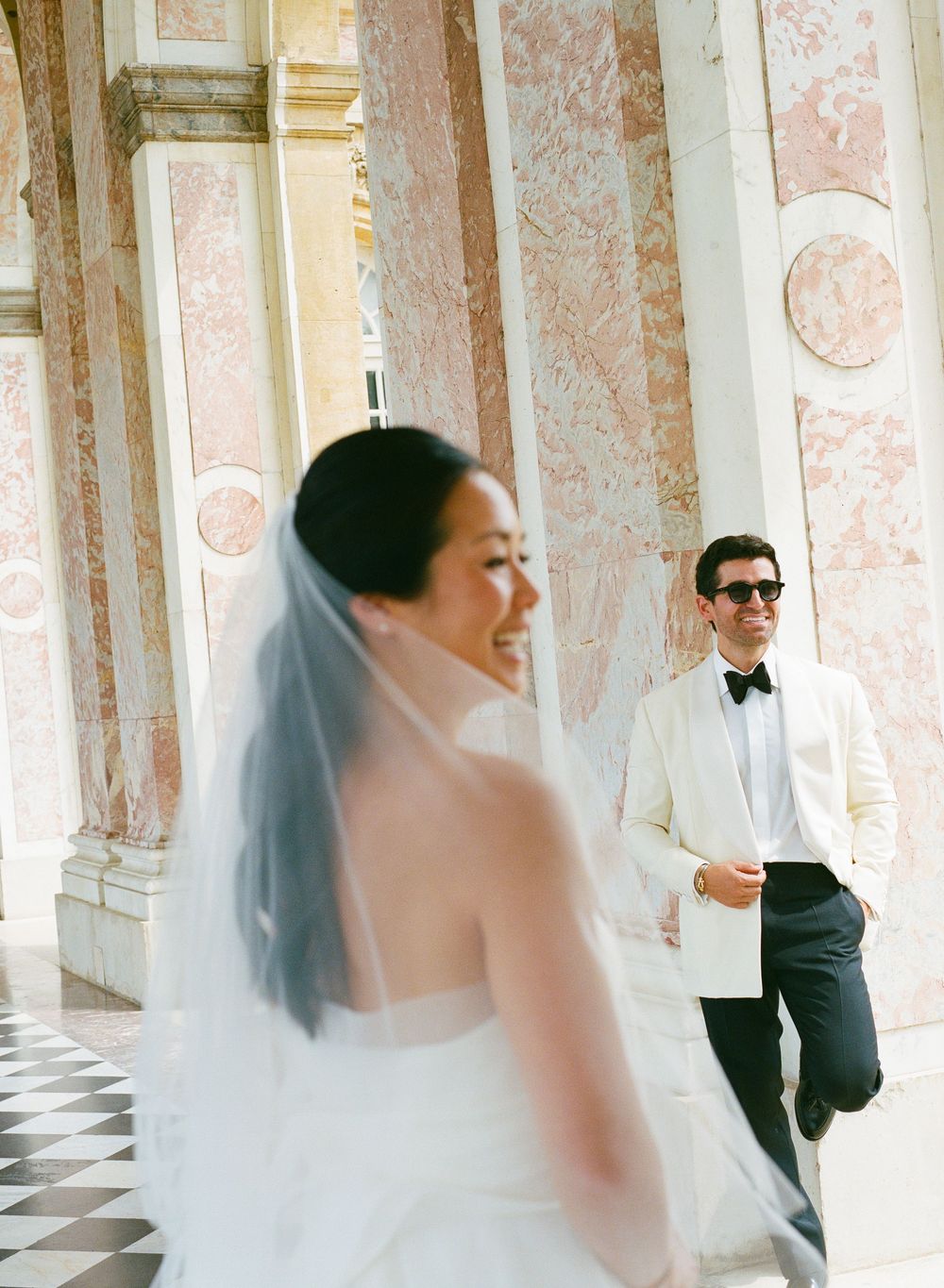Bride in white gown and veil laughs. Candid wedding photography. Le Grand Trianon. Chateau de Versailles wedding photos, film photos