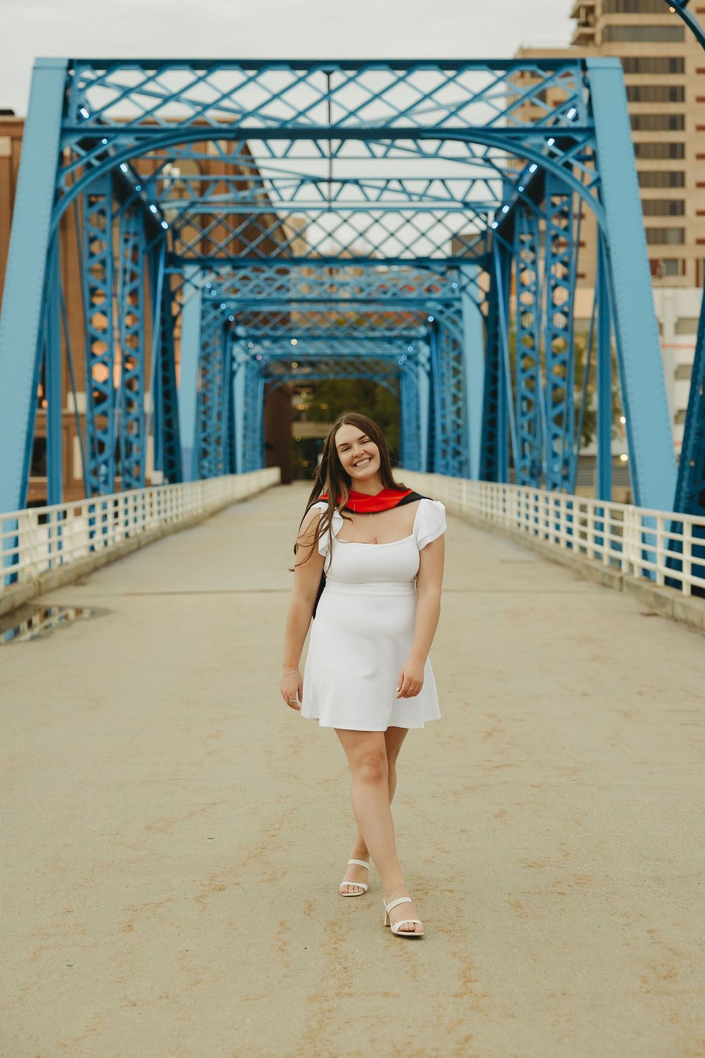 Young woman in white dress and red scarf smiling on the Blue Bridge in Grand Rapids, Michigan.