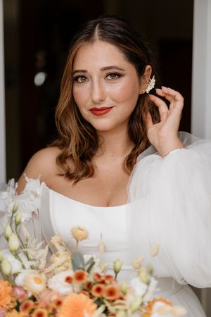 Elegant bridal portrait with white dress and peach-colored floral arrangements.