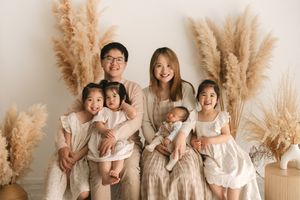 Happy Asian family of six posing together with pampas grass decor in neutral tones for a professional portrait.