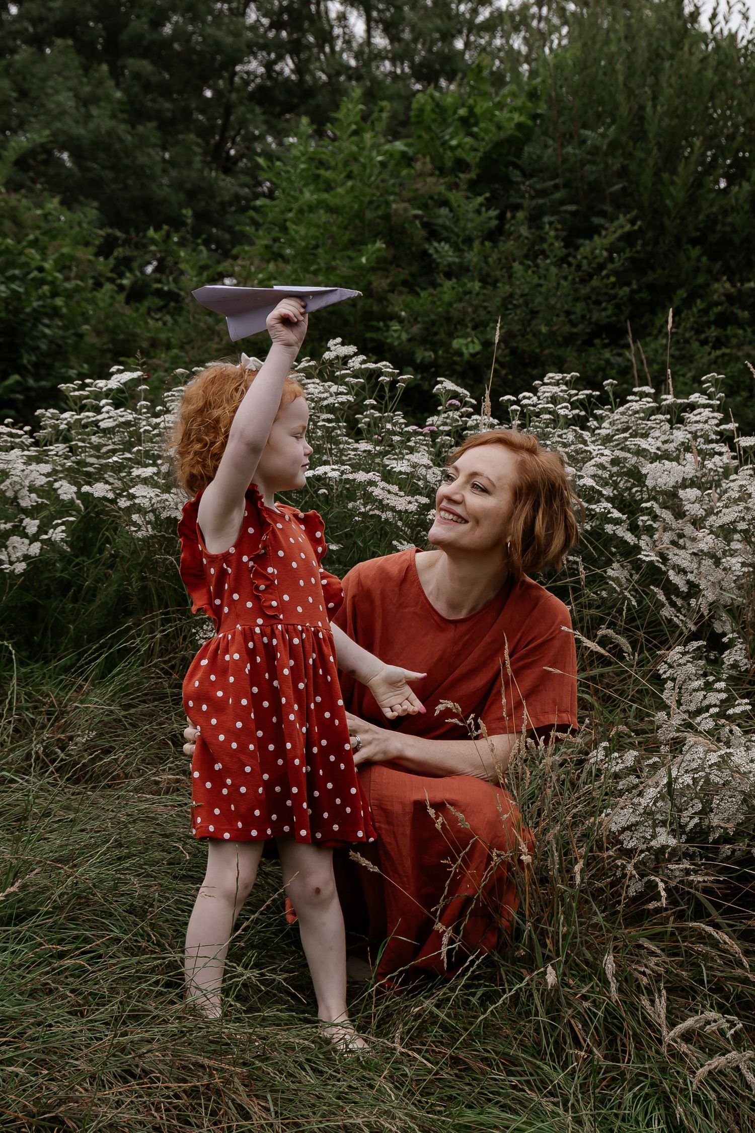 Mother and daughter playing with a paper plane during an outdoor family photoshoot in Woerden