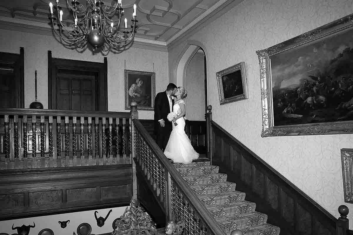 Bride and groom share an intimate kiss at the top of the grand staircase at Armathwaite Hall.
