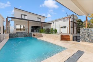 Contemporary home featuring a sparkling backyard pool with timber deck and stone feature wall.