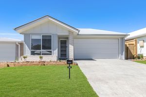 Modern single-story home with white render, grey garage door, manicured lawn, and concrete driveway under blue sky.