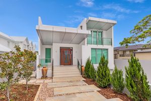 Modern two-story white rendered home with timber front door and manicured garden entry.