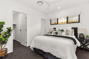 Comfortable bedroom with white bedding, carpet floors, ceiling fan, and walk-in wardrobe entrance.