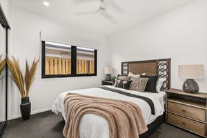 Elegant master bedroom with timber bedhead, neutral tones, ceiling fan, and decorative lamps.