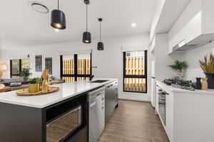 Sleek modern kitchen with black island bench, pendant lights, and stainless steel appliances.