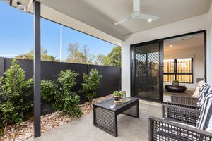 Covered alfresco area with outdoor furniture, ceiling fan, garden views, and sliding screen door.