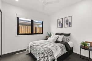 Modern bedroom with black and white bedding, carpet floors, ceiling fan, and framed wall art.