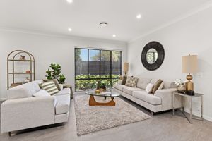 Bright living room with white sofas, round mirror, timber floors, and garden-facing window.