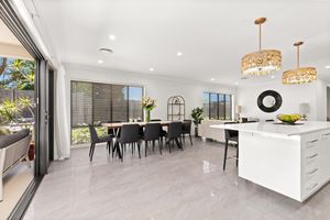 Bright open-plan kitchen and dining area with marble floors, gold pendant lights, and garden views.