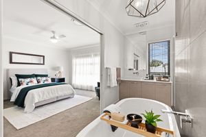 Elegant master bedroom with ensuite featuring a freestanding bathtub, tiled walls, and ceiling fan.