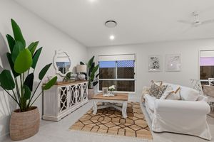 Bright coastal living room with white slipcovered sofa, timber coffee table, and tropical indoor plants.