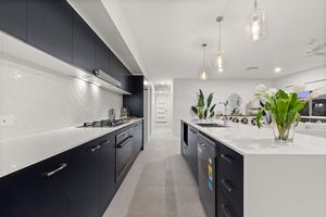 Stylish navy and white kitchen with herringbone tile splashback, gas cooktop, and waterfall island bench.
