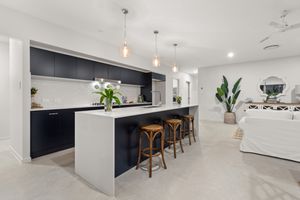 Contemporary open-plan kitchen featuring navy cabinets, white island with bar stools, and pendant lights.