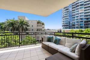 Spacious balcony with outdoor sofa and city views surrounded by lush greenery.