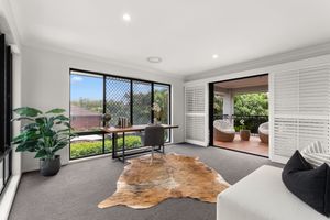Home office with carpet, cowhide rug, mesh window, and shuttered doors to outdoor patio.