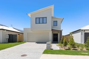Modern two-storey home with double garage and concrete driveway under blue sky.