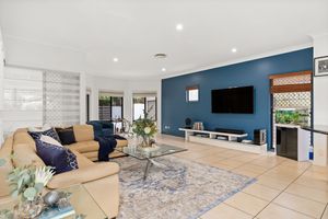 Spacious living room with teal accent wall, mounted TV, beige leather sofa, and tiled floors.