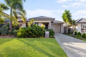 Attractive suburban home with palm trees, manicured lawn, and gravel driveway on a sunny day.