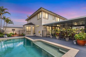 Stunning two-story home with a sparkling swimming pool and covered outdoor entertaining area at twilight.