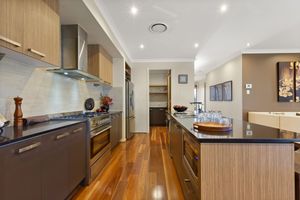 Sleek galley kitchen with dark benchtops, stainless steel appliances, and polished hardwood floors.