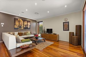 Bright living room with white sectional sofa, polished hardwood floors, and Asian-inspired wall art.