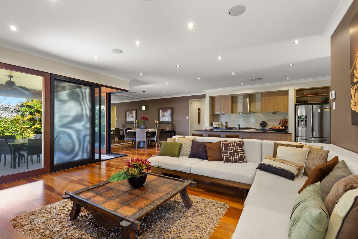 Spacious open-plan living room with large sectional sofa, hardwood floors, and view to kitchen.