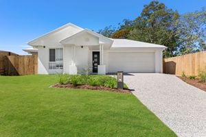 Charming white single-storey home with double garage and gravel driveway on green lawn.
