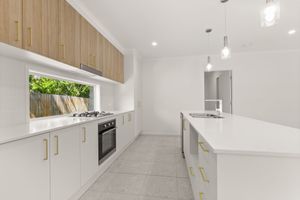 Modern white kitchen with timber upper cabinets, island bench, and gold hardware accents.