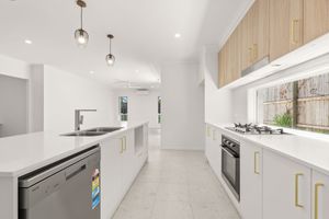 Bright modern kitchen with white cabinetry, timber accents, island bench, and gold handles.