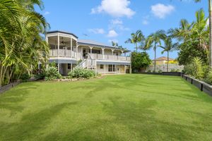 Large Queensland home with wrap-around verandah surrounded by lush tropical gardens and expansive lawn.