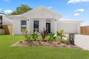 Modern white rendered home with manicured lawn, tropical garden landscaping, and double garage.