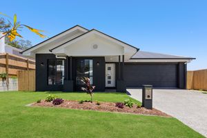 Stylish single-storey home with dark garage door, white facade, and neat front garden.