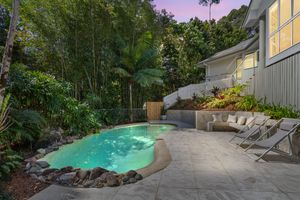 Serene backyard pool area with tropical gardens and lounge chairs at dusk in a Queensland home.