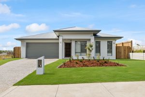 Modern single-story Australian home with gray roof, double garage, manicured lawn, and decorative garden bed on a sunny day.