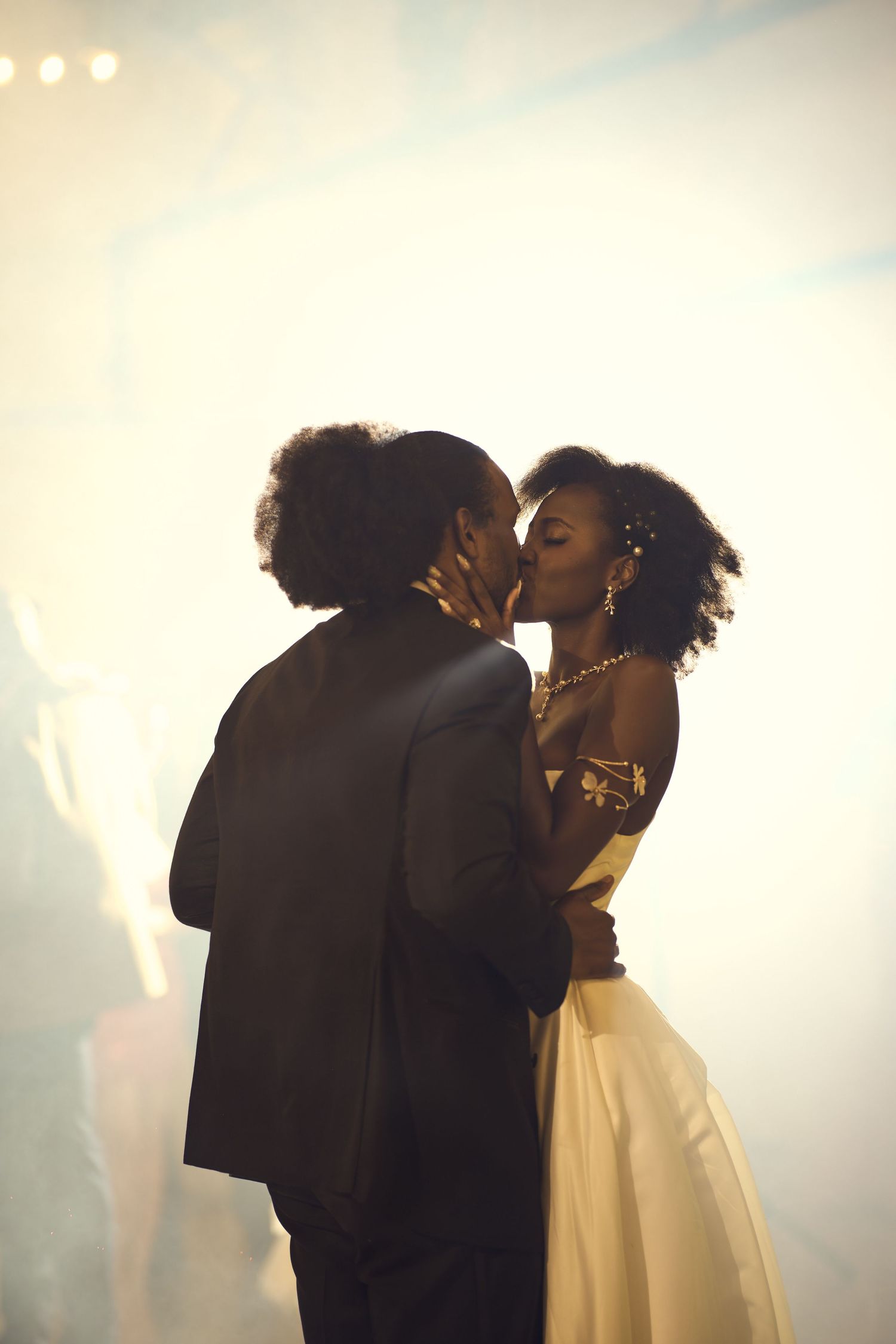 A couple sharing a romantic first dance kiss at their wedding reception amid soft glowing light.